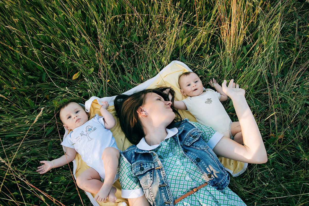 Mother Laying with Babies on a Blanket on the Grass